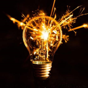 A glowing light bulb with sparks bursting from the filament against a dark background, symbolising innovation and ideas.